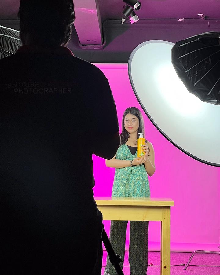 DCOP student filming a product presenter on a pink studio set with professional lights