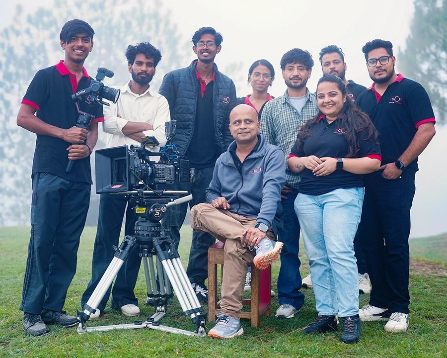 Commercial filmmaking students and faculty gathered around a cinema camera during an outdoor production