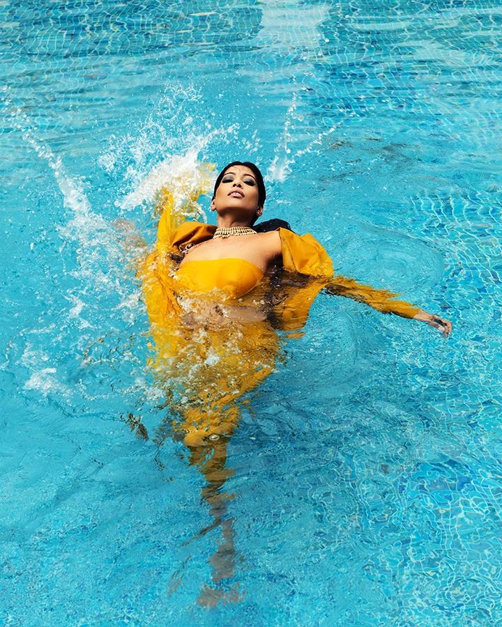 Fashion model in a yellow dress posing in a swimming pool for a location shoot