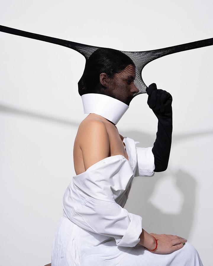 Conceptual fashion portrait in monochrome styling with an experimental mesh headpiece
