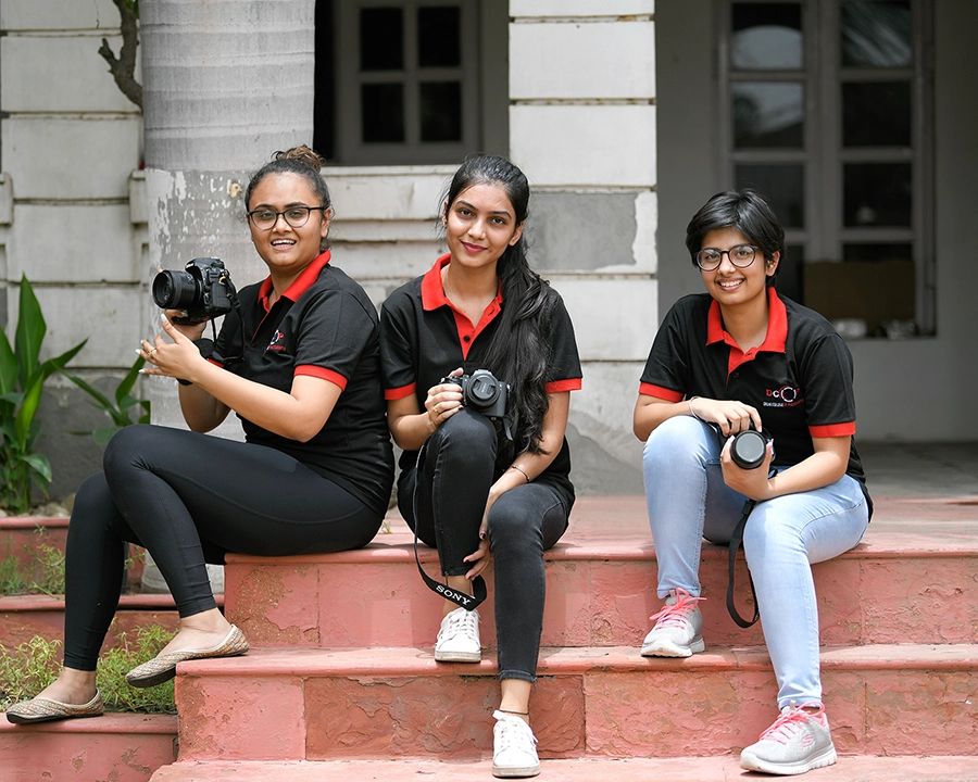 Three Foundation Photography students holding cameras after an outdoor practice session